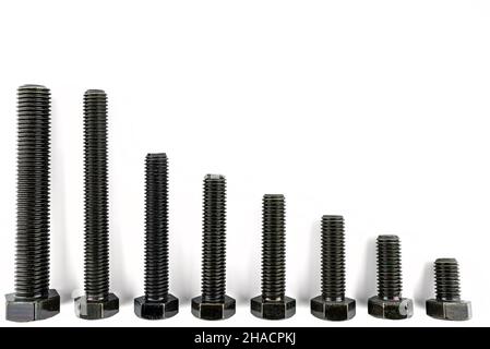 Background made of black screws with a hardness of 4.8, isolated on a white background, visible small and large screws. Stock Photo
