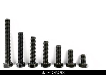 Background made of black screws with a hardness of 4.8, isolated on a white background, visible small and large screws. Stock Photo