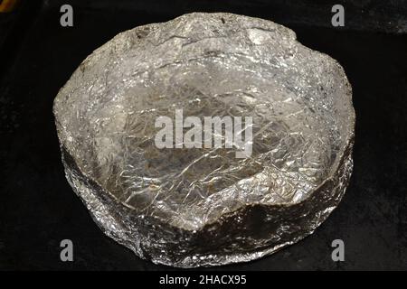 Baking Mold Homemade Silver Color Round Crumpled Aluminum Foil for Baking Cake Tortillas on Black Background. DIY. Kitchen Tools. Isolated. Stock Photo