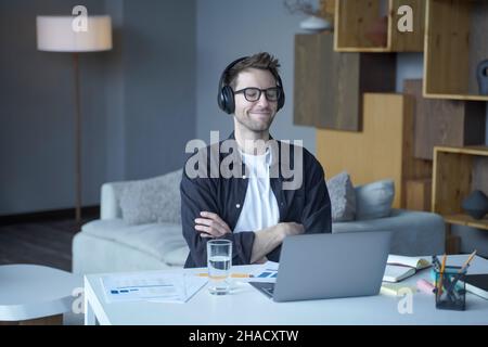 Young happy austrian male freelancer in headphones enjoying listening to music at home office Stock Photo