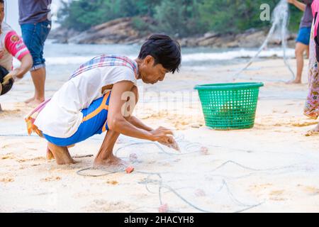 Phuket Thailand December 2021, the local fisherman on the beach of Naithonbury empty their fishing nets, Thai fisherman on the beach.  Stock Photo
