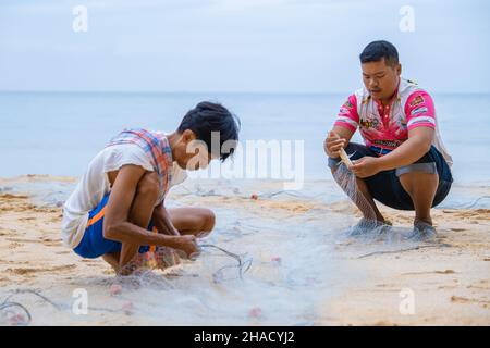Phuket Thailand December 2021, the local fisherman on the beach of Naithonbury empty their fishing nets, Thai fisherman on the beach.  Stock Photo