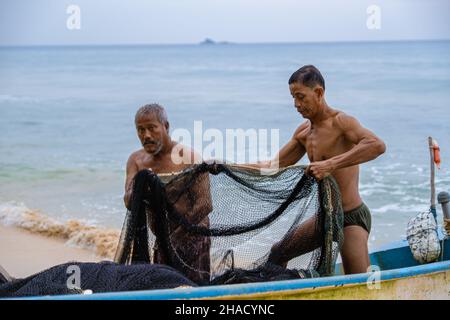 Phuket Thailand December 2021, the local fisherman on the beach of Naithonbury empty their fishing nets, Thai fisherman on the beach.  Stock Photo