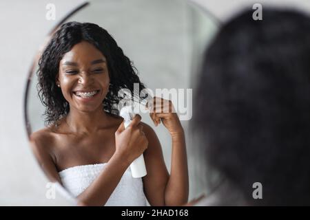 Happy young black woman using hair spray Stock Photo