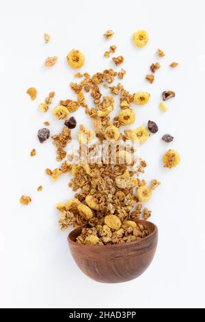 crunchy granola for breakfast, tasty granola poured out of wooden bowl isolated on white background, concept healthy food Stock Photo