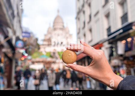 Hand holding a french macaroon cookie, Macaron, on the street of Paris Stock Photo