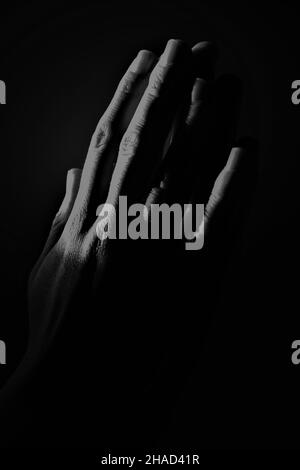 Abstract hands pressed together in stark black and white with only the fingers highlighted