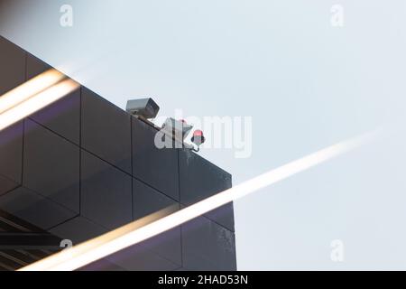CCTV cameras on the roof of an office building on the street on a cloudy day against the background of a gray sky. Close-up Stock Photo
