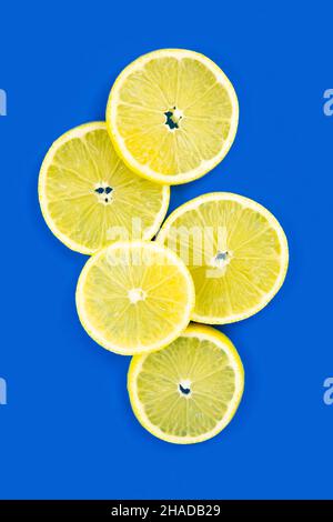 Ripe juicy lemons, orange and green leaves on bright yellow background. Flat lay, top view, copy space Stock Photo