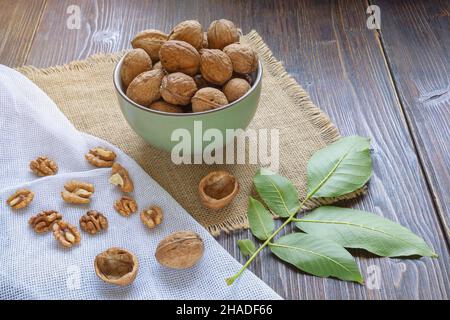 Whole walnuts and kernels on dark rustic table.  Leaves of walnut tree Stock Photo