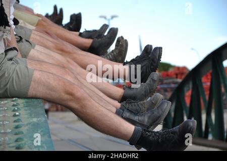 Legs of boys in the air in a row on the bridge. army military legs detail feet group men military no model release row shoes. Stock Photo