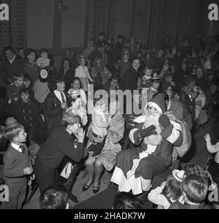 1965, historical, a santa claus in costume, mask and beard, with sack of presents, sitting on his wooden sledge which is being pushed into the middle of a village hall to the delight of the young children, who have just had a christmas party. Stock Photo