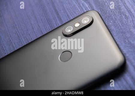A black smartphone with two cameras and fingerprint reader. Dual camera smartphone close up on blue wood table Stock Photo