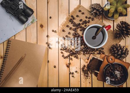 Cup black coffee and coffee beans, Coffee grinder, map, binoculars on the table wooden Stock Photo