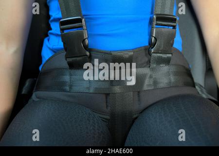 Young woman in car restrained with a harness for persons with special needs. Stock Photo