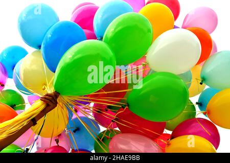 human's hand holding bunch of multicolored balloons in the city  festival,isolated on white Stock Photo
