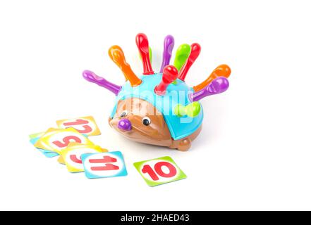 Childrens toy for the development of motor skills in the form of a hedgehog with multi-colored needles and cards on a white background. Stock Photo