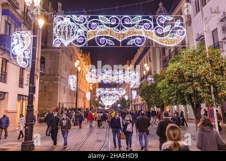 Seville, Spain - December 03,2021: Unidentified People walking around Seville Cathedral of Saint Mary of the See at christmas time. People wearing pro Stock Photo