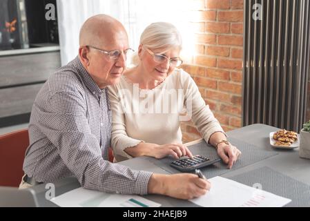Retired senior couple checking and calculate financial billing. Financial paperwork, tax, increasing prices Stock Photo