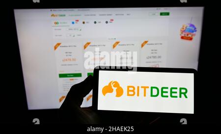 Person holding smartphone with logo of Singaporean blockchain mining company Bitdeer Group on screen in front of website. Focus on phone display. Stock Photo