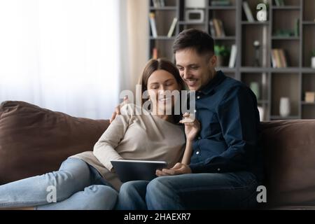 Happy relaxed young family couple using digital computer tablet. Stock Photo
