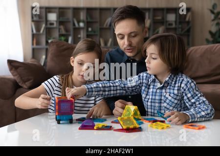 Happy family playing with magnetic constructor at home. Stock Photo