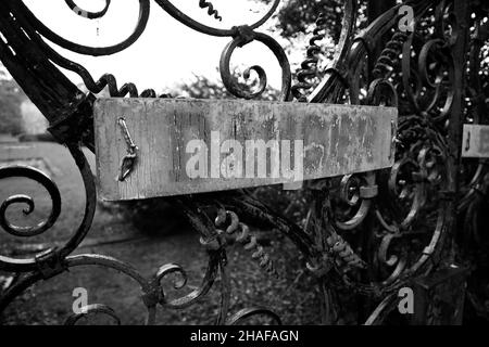 a creepy old "danger" sign on a wrought iron gate in black and white Stock Photo
