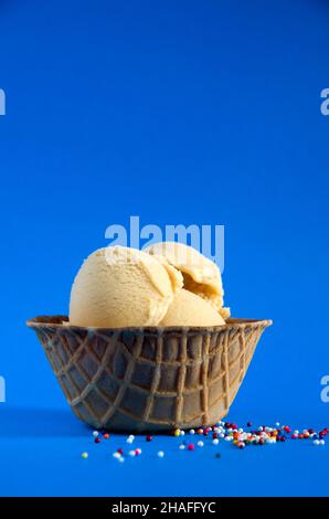 Sea Salted Caramel Gelato in a Waffle Bowl with Blue Background and Colored Candies Vertical Stock Photo