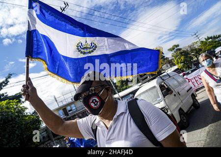 San Salvador, El Salvador. 12th Dec, 2021. A protestor waves the El Salvador flag during the protest. Demonstrators took to the streets to protest the government of Nayib Bukele and his policies. Recently the United States Biden administration accused the Salvadoran government officials of corruption and a secret truce with organized crime such as MS-13 and Barrio 18 to lower homicide records. (Photo by Camilo Freedman/SOPA Images/Sipa USA) Credit: Sipa USA/Alamy Live News Stock Photo