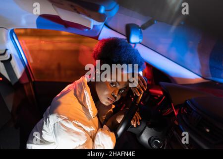 Tired african woman lying on steering wheel, sad depressed black female sitting in car at night Stock Photo
