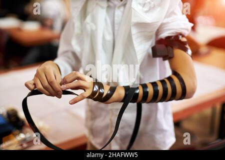 Hand wrap tefilin around the other hand. Jewish teenager 13 years old celebrates bar mitzvah Stock Photo