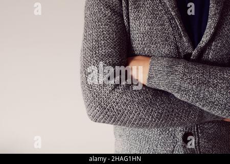 A man with crossed arms in a cardigan on a light background. Front view. Copy space. Stock Photo