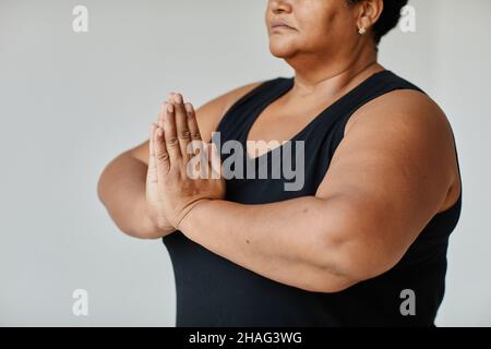 Minimal close up of black senior woman meditating while doing yoga indoors, focus on hands in balance Stock Photo