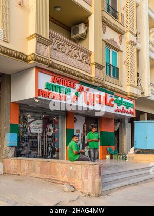 Hurghada, Egypt - May 31, 2021: Street view of Hurghada with men relaxing outside a pharmacy in Egypt. Stock Photo