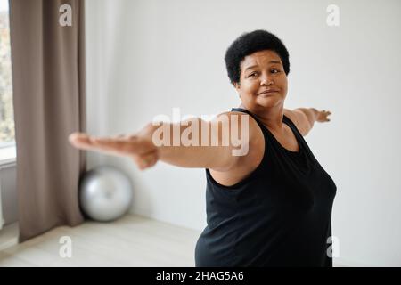 Minimal waist up portrait of active senior woman working out indoors and stretching Stock Photo