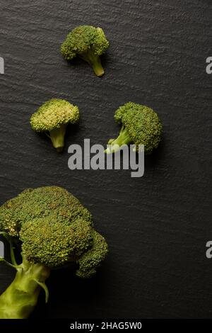 vegetable concept a few pieces of broccolis being lay on the black background. Stock Photo