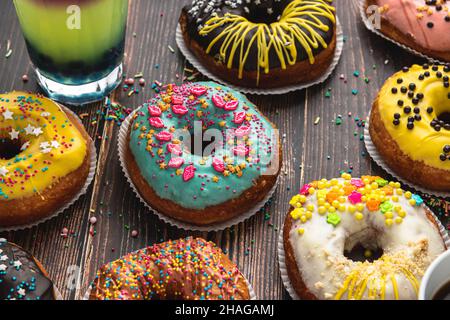 Top view of donuts in various colors and flavors on wooden table Stock Photo