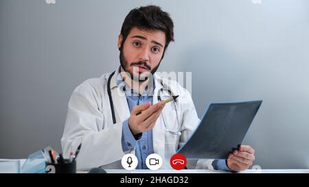 Laptop videocall screenshot of a young doctor talking about a X-ray of a pelvis. Stock Photo