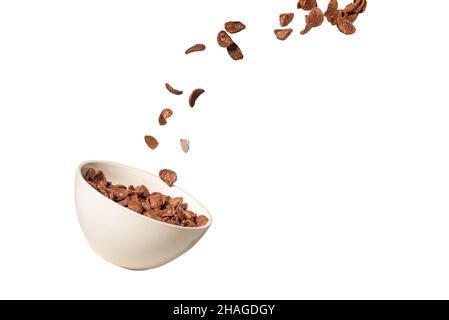 Chocolate corn flakes falling to the white bowl isolated on white. Motion. Copyspace. Stock Photo
