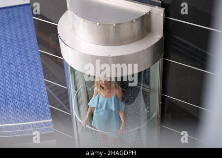 Beautiful woman in the glass elevator of the building Stock Photo