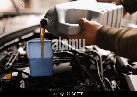 Pouring of car oil from canister against white background Stock Photo