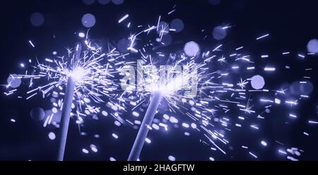 Bright glittering sparkler on blurred bokeh background Stock Photo
