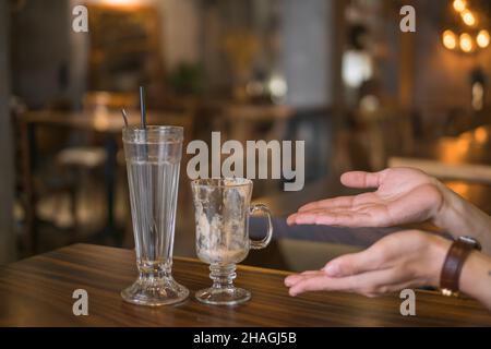 Two empty iced coffee glass cups on the table in coffee shop and hands showing on glasses. High quality photo Stock Photo
