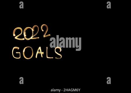 2022 goals, light painting golden 2022 goals written against black background. Long exposure photography. 'New year coming' concept photo.