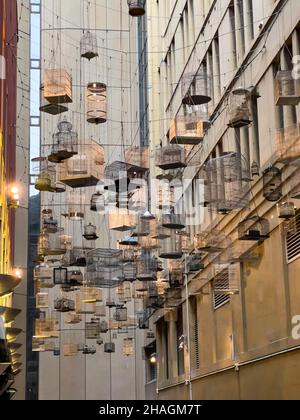 Forgotten Songs is an artistic installation of empty birdcages hanging in the sky on the angle of Place lane way, Sydney NSW Australia Stock Photo
