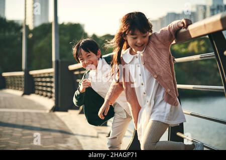 two happy asian children having good time playing in city park