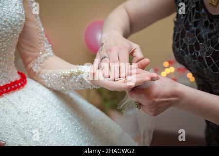 He ties a ribbon and money over his hand. The bride ties a ribbon and money over her hand . Stock Photo