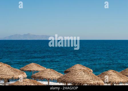 Straw beach umbrellas against the blue sea and sky Stock Photo