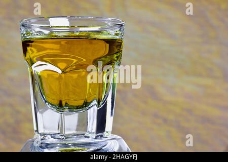 On a beige background on the left side of a glass with whiskey close-up. On the right is an empty space for an inscription Stock Photo