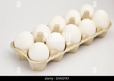 Ten chicken eggs lie in two rows in a cardboard tray. The tray lies obliquely Stock Photo